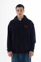 Buzo hoodie negro con capucha y bolsillo canguro. Estampado trasero con un monstruo caricaturesco en skate y la frase "Skate and Destroy". Logo VERNAL CLUB en el pecho.