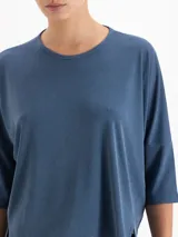 Remera de silueta relajada confeccionada en tela de punto suave. Presenta escote redondo, mangas 3/4, recorte estratégico en la espalda y tajos laterales que aportan movimiento y una caída fluida.