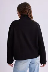Buzo de punto en color negro, con cuello alto y puños y ruedo acanalados. Presenta un diseño de corte recto y tejido elástico.