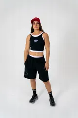 Musculosa deportiva ajustada color negro, con doble tela y tirantes finos. Presenta un pequeño logo circular en el pecho.