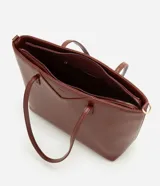 Cartera tipo shopper grande de Satinato, confeccionada en poliuretano con textura efecto crocco en color marrón. Presenta doble asa fija, correa larga desmontable con herrajes dorados y cierre superior por cremallera.