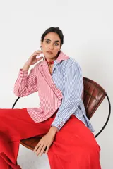 Camisa a rayas rojas y blancas en un lado y azules y blancas en el otro, con corte en A y abertura central con botonadura doble.