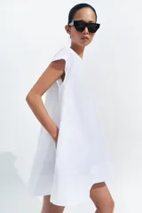 Vestido corto Zara de la colección ZW Collection, color beige, confeccionado en mezcla de algodón. Presenta cuello redondo, manga corta, bolsillos laterales ocultos en costura, bajo evasé y cierre en la espalda con cremallera.