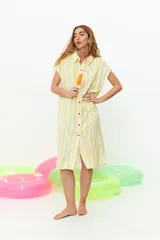 Vestido camisero amarillo con rayas verticales blancas, sin mangas y con botones rojos.