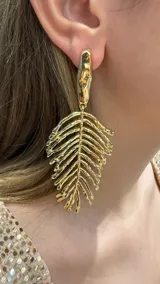 Caravanas colgantes de diseño orgánico en forma de hoja con acabado texturizado y brillante en tono dorado.