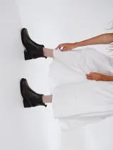 Bota corta de cuero negro con acabado efecto envejecido, punta cuadrada y tacón geométrico. Cuenta con cierre lateral para un calce práctico.