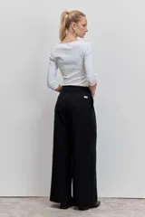 Pantalón de vestir negro con rayas verticales blancas, de corte recto y tiro alto.