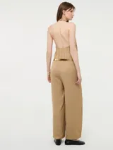 Mono color beige con escote halter, corte holgado, cinturón dorado y pantalones palazzo.