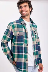 Camisa de franela a cuadros en tonos verde, azul y beige, con dos bolsillos frontales con solapa abotonada.