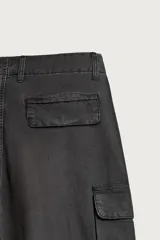 Pantalón cargo de corte relaxed fit, color negro con efecto lavado y estampado de salpicaduras blancas. Cuenta con bolsillos laterales con solapa en las perneras, pinzas en las rodillas y cierre frontal con botón y cremallera.