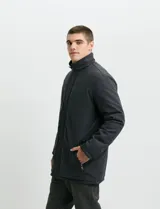 Campera de estilo Harrington en color verde oscuro, con cuello alto, cierre frontal y solapa con botones.
