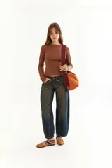 Top de manga larga color marrón, confeccionado en tejido acanalado con cuello bote. Presenta costuras decorativas expuestas a lo largo de las mangas, creando un efecto de relieve.