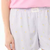 Conjunto de pijama para mujer compuesto por una remera rosada de manga corta con cuello redondo y estampa pequeña en el pecho, y un short liviano con estampa de rayas y pequeños motivos de limones sobre fondo blanco y lila.