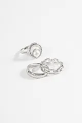 Set de tres anillos plateados de diseño variado: uno con perla central, uno tipo cadena de eslabones y uno liso con pequeñas incrustaciones de cristales.