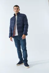 Campera inflada azul marino de nylon con cuello alto, cierre frontal con cremallera, bolsillos laterales con cierre y logo estampado en el pecho. El modelo usa talle M.