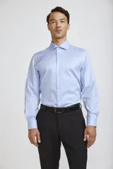 Camisa de vestir blanca de corte clásico, con cuello rígido, cierre frontal de botones y mangas largas con puños abotonados.