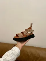 Sandalias de cuero color beige con plataforma de goma negra, tiras anchas con hebillas ajustables y tira trasera con velcro.