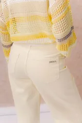 Pantalón de jean de tiro medio-alto y pierna amplia con caída recta, color amarillo manteca, con diseño clásico de cinco bolsillos y cierre delantero con botón.