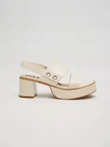 Sandalias de plataforma con taco cuadrado de 6 cm y base de 3 cm. Presentan dos tiras anchas en el empeine con detalles de doble argolla metálica en los laterales y una correa trasera con elástico para mayor ajuste.