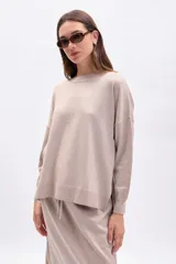 Buzo de tejido de punto color beige con hilo de lurex que le da un brillo sutil. Presenta cuello redondo, mangas largas y un calce holgado.