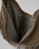 Cartera tipo hobo de gran tamaño en color negro, confeccionada en gamuza con diseño de flecos largos en los laterales y base. Presenta un asa superior trenzada con detalles artesanales y cierre superior para mayor seguridad.