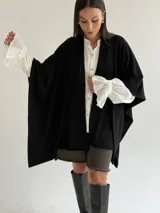 Ruana de tejido de punto trenzado en color crudo, con diseño abierto, corte holgado y mangas amplias tipo kimono.