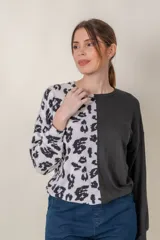 Buzo de manga larga con cuello redondo, combinado en dos tonos: negro liso en la mitad derecha y estampado animal print blanco y negro en la mitad izquierda.