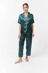 Conjunto de pijama verde esmeralda de satén con ribetes blancos, compuesto por camisa de manga corta con botones y pantalón capri.
