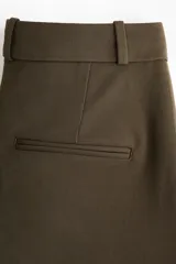 Pantalón sastrero de sarga en color verde oscuro, de corte recto con pliegues frontales, cintura clásica con presillas y bolsillos al bies.