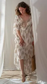 Sandalia chata color beige con tira central en forma de T adornada con piedras facetadas en tonos blancos iridiscentes y rosados pálidos, engarzadas en metal dorado.