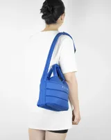 Bandolera azul acolchada con correa ajustable y asa de mano.