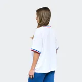 Remera de fútbol Umbro del Club Nacional de Football para mujer. Diseño azul con detalles tricolor en cuello y mangas. Incluye logo de Umbro y escudo del club en el frente.