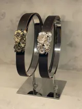Cinturón de cuero marrón con hebilla de metal dorada o plateada con diseño de flores y colibríes.