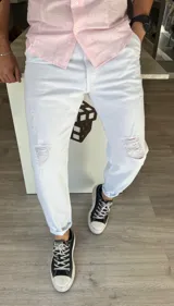 Pantalón slouchy de mezclilla blanca para hombre, con diseño amplio y relajado, talle medio y detalles de roturas en las rodillas.