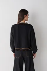 Cardigan de punto color marrón con detalles de ribete en color verde oliva en cuello, puños, ruedo y tapeta de botones. Presenta cierre frontal con botones grandes y un pequeño bordado en el pecho.