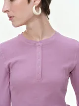 Remera de manga larga confeccionada en tejido acanalado, con escote redondo y cierre frontal con botones. Presenta un ajuste entallado al cuerpo.