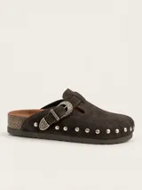 Zueco de gamuza marrón oscuro, forrado en cuero vacuno, con tira ajustable con hebilla metálica decorativa y tachas plateadas alrededor de la suela.