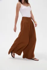 Pantalón ancho de poliéster color marrón, de tiro alto con pinzas en la cintura y punto smock en la parte posterior.