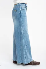 Jean de corte wide leg con tiro medio, confeccionado en denim de algodón. Presenta un diseño de pierna ancha con costuras verticales frontales que estilizan la silueta, cierre de botón y cremallera, y bolsillos clásicos.