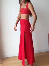 Falda larga tejida color marrón con brillo metálico, corte al cuerpo, abertura alta en la pierna y recortes laterales con cordones ajustables.