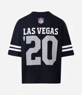 Remera deportiva de corte oversized, color negro, con estampado gráfico en la espalda del equipo Las Vegas Raiders de la NFL. Presenta cuello redondo, mangas cortas con detalles de rayas blancas y logo de la NFL en la parte superior trasera.