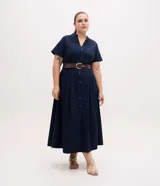 Vestido midi chemise azul marino de manga corta, con cuello padre, botonadura frontal completa con botones metalizados y pliegues en la falda. Incluye un cinturón marrón.