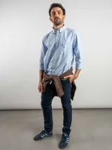 Camisa de corte regular confeccionada en tejido Oxford de algodón, con diseño de rayas verticales finas. Presenta cuello abotonado, cierre frontal con botones y un bolsillo en el pecho.