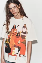 Remera oversize de algodón color crudo con cuello redondo y manga corta. Presenta una ilustración artística estampada y bordada en el frente que representa a un grupo de mujeres.