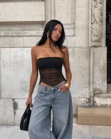 Top strapless negro con diseño ajustado al cuerpo y cuerpo de tela translúcida fruncida con bajo asimétrico en punta.