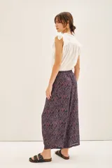 Pantalón tipo babucha o pirata de viscosa, color azul marino con estampado en tonos rojizos y blancos. Presenta un corte amplio, bolsillos laterales y cintura elástica.