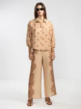 Pantalón palazzo negro con estampado de sirenas en color beige.