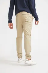 Pantalón cargo color beige de corte slim, con cierre y botón frontal, y bolsillos laterales tipo cargo con cierre.