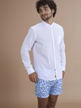 Camisa blanca de manga larga con cuello mao y cierre frontal de botones.