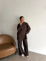 Conjunto de dos piezas compuesto por un buzo con capucha de corte holgado y mangas largas, y un pantalón de corte recto y tiro alto. Ambas prendas son de color marrón liso.